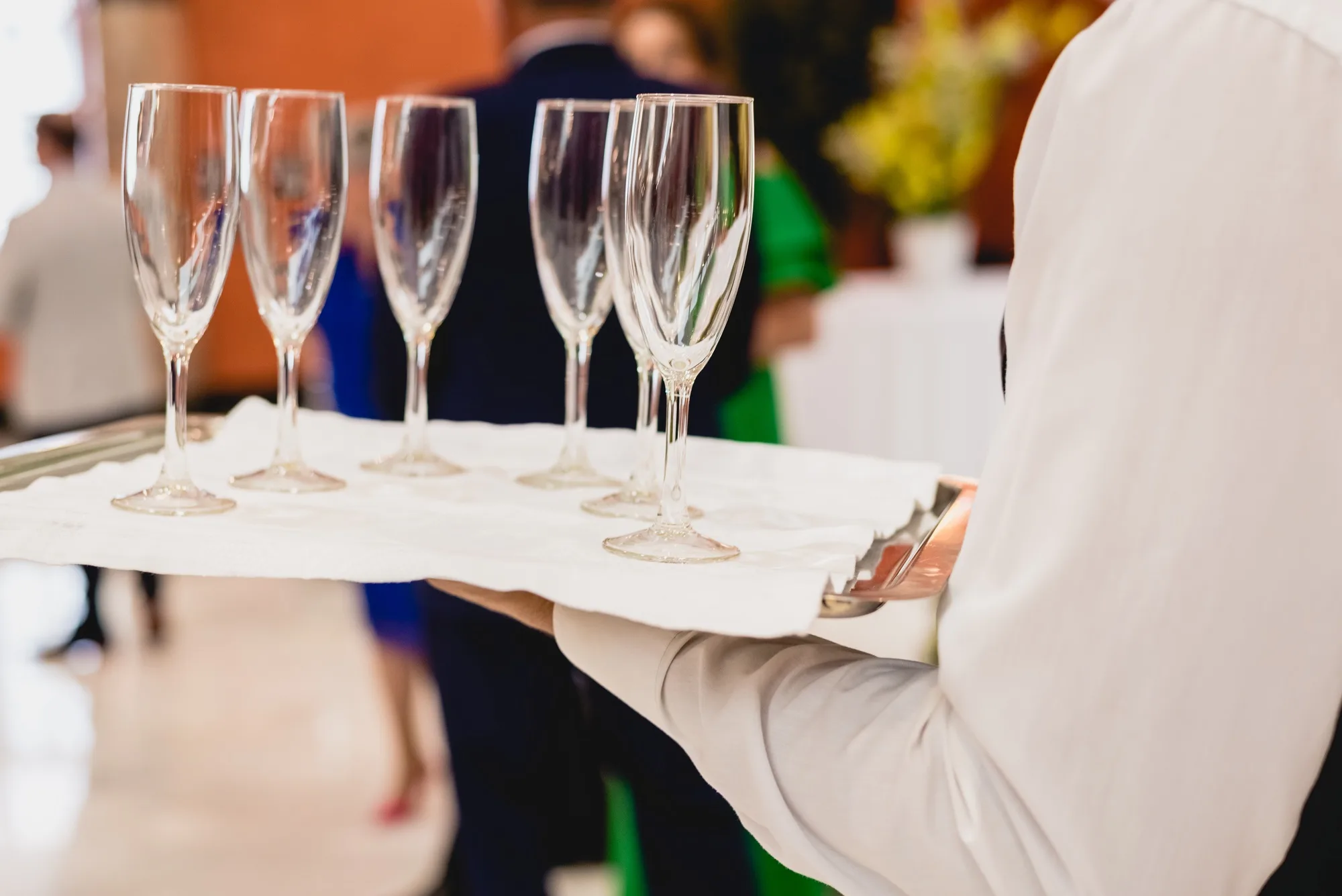 Glasses of champagne ready to be served by a waiter.